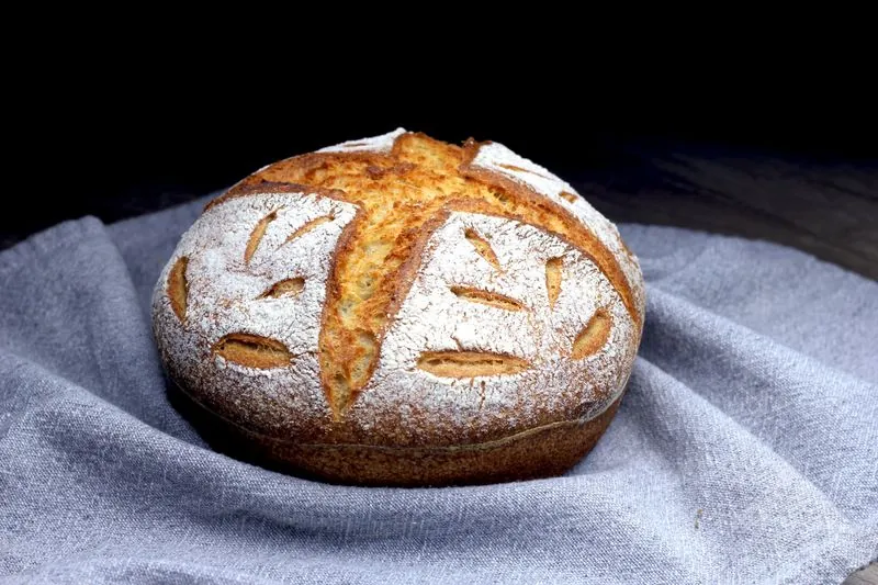 A round loaf dusted with flour on a grey cloth