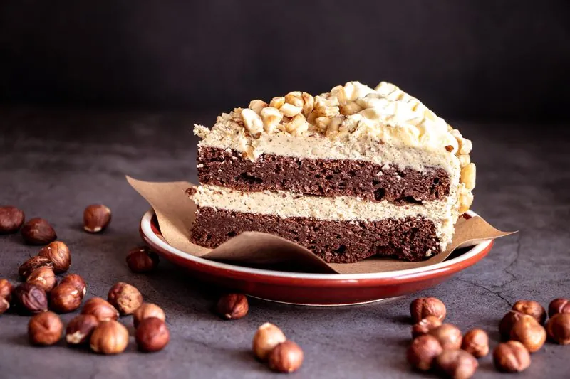 A slice of chocolate layer cake with hazelnuts